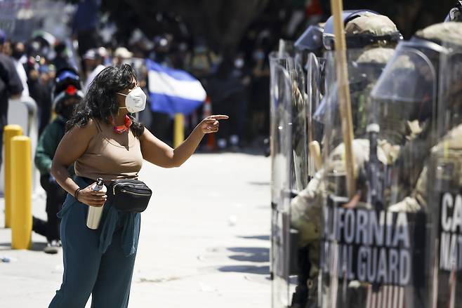 미국 캘리포니아주 주방위군이 8일(현지시간) 로스앤젤레스에서 이민단속 반대 시위에 참여한 시위자와 대치하고 있다. 이날 도널드 트럼프 미국 대통령은 60년만에 처음으로 주지사 요청 없이 시위 진압을 위해 주방위군 2000명 배치를 명령했다. [EPA]