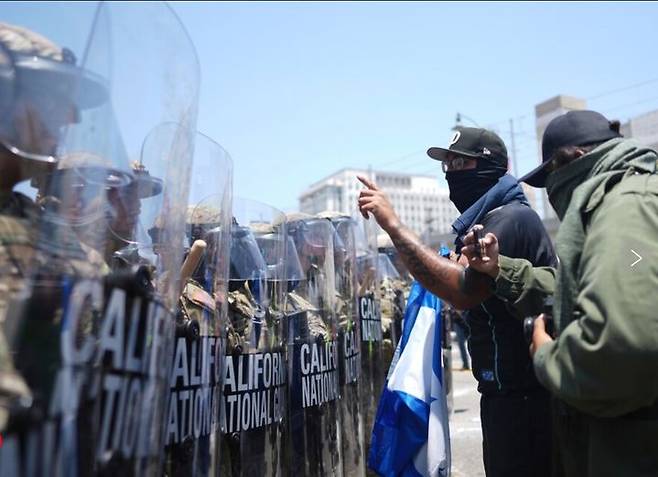 [로스엔젤레스=AP/뉴시스] 8일(현지 시각) 미국 캘리포니아주 로스엔젤레스에 투입된 주 방위군이 마스크를 쓴 이민자 강제 추방 반대 시위대와 대치하고 있다. 2025.06.09. *재판매 및 DB 금지