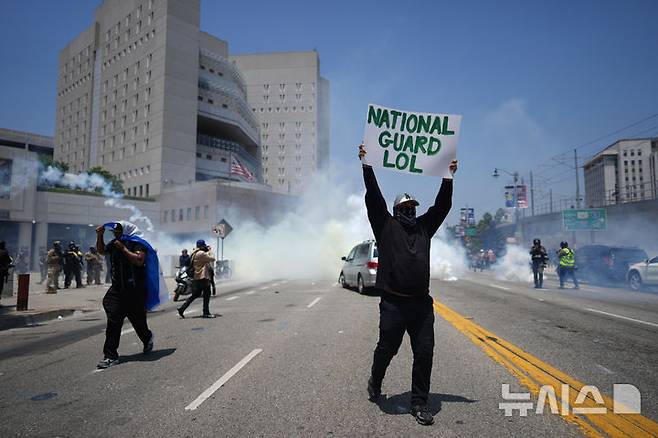 [로스앤젤레스=AP/뉴시스] 8일(현지 시간) 미 캘리포니아주 로스앤젤레스 도심의 메트로폴리탄 구치소 인근에서 이민세관단속국(ICE)의 불법 이민자 단속 및 체포에 항의하는 시위대가 최루 가스 속에서 시위하고 있다. 도널드 트럼프 대통령은 불법 이민자 단속에 항의하는 시위에 참여하는 사람들은 마스크를 착용해서는 안 된다고 밝혔다. 2025.06.09.