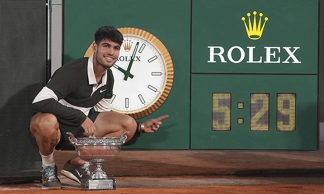 카를로스 알카라스가 9일 프랑스 오픈 남자 단식 결승에서 역대 최장인 5시간29분 혈투 끝에 우승한 뒤 게임 시간을 알리는 시계를 가리키며 기념촬영을 하고 있다. 파리=AP연합뉴스