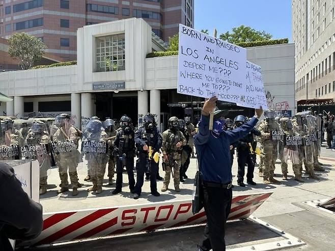 미 LA에서 불법이민 단속에 항의하는 시위대와 이를 막아선 주방위군 (로스앤젤레스=연합뉴스) 임미나 특파원 = 8일(현지시간) 미국 로스앤젤레스(LA) 도심의 연방 구금시설인 '메트로폴리탄 디텐션 센터'(Metropolitan Detention Center, 이하 MDC) 앞에서 주방위군이 시위대와 대치하고 있다. 시위대는 미 이민세관단속국(ICE)의 대대적인 불법이민자 단속에 반발하는 시위를 사흘째 벌이고 있다. mina@yna.co.kr