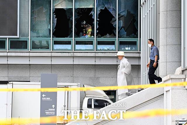 깨진 창문 앞으로 스님이 지나가고 있다.