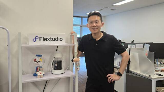 권오림 본부장이 플렉스튜디오 CI를 배경으로 포즈를 취했다.