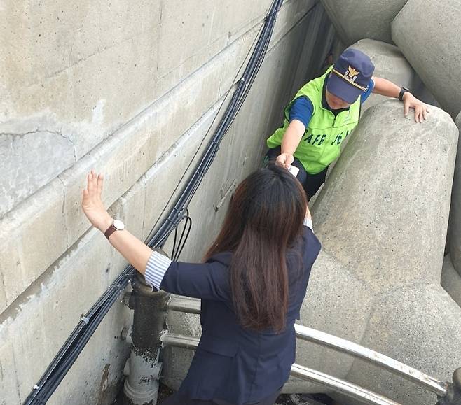 제주해안경비단 박진우 경위가 테트라포드 밀집 지역에서 외국인 관광객의 핸드폰을 찾아 건네주고 있는 모습