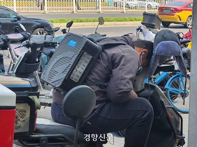 지난 3월 중국 베이징의 한 노동자가 전동차 위에서 휴식을 취하고 있다.  베이징 | 박은하 특파원