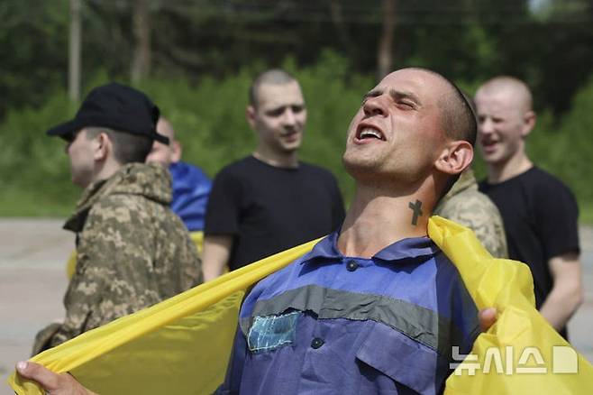 [체르느히우=AP/뉴시스] 9일(현지 시간) 우크라이나 체르느히우에서 러시아와의 포로 교환으로 석방된 한 우크라이나 군인이 국기를 몸에 두른 채 환호하고 있다. 러시아와 우크라이나가 25세 미만과 중상자 포로를 교환했다. 2025.06.10.