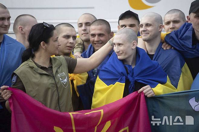 [체르느히우=AP/뉴시스] 9일(현지 시간) 우크라이나 대통령실이 제공한 사진에 체르느히우에서 러시아와의 포로 교환으로 석방된 한 우크라이나 군인들이 국기를 몸에 두른 채 미소를 짓고 있다. 러시아와 우크라이나가 25세 미만과 중상자 포로를 교환했다. 2025.06.10.