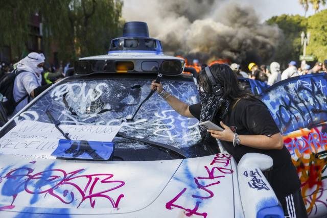 8일(현지 시간) 캘리포니아주 로스앤젤레스(LA)에서 정부의 불법 이민 단속에 반발한 한 사람이 자율주행차 웨이모를 부수고 있다. EPA연합뉴스