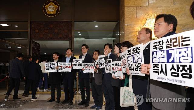 더불어민주당 의원들이 서울 여의도 국회 본회의장 앞에서 상법개정안 상정을 촉구하는 팻말을 들고 구호를 외치고 있다. 연합뉴스