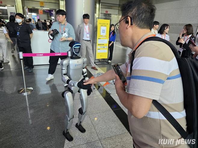 한 관람객이 ‘스마트테크 코리아 2025’ 행사장 입구에 설치된 로봇과 악수를 나누고 있다. 정우진 기자