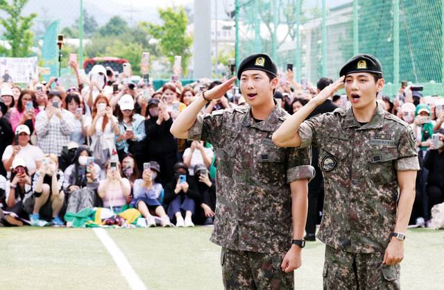 그룹 방탄소년단(BTS) 멤버 RM(왼쪽)과 뷔가 10일 강원도 춘천 신북읍체육공원에서 팬과 취재진을 향해 거수경례로 전역 인사를 하고 있다. 연합뉴스