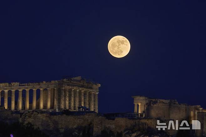 [아크로폴리스=AP/뉴시스] 10일(현지 시간) 아테네 아크로폴리스 파르테논 신전 뒤로 스트로베리 문이 떠오르고 있다. 스트로베리 문은 북미 원주들이 딸기를 수확하는 시기인 6월에 뜨는 달을 의미한다. 2025.06.11.