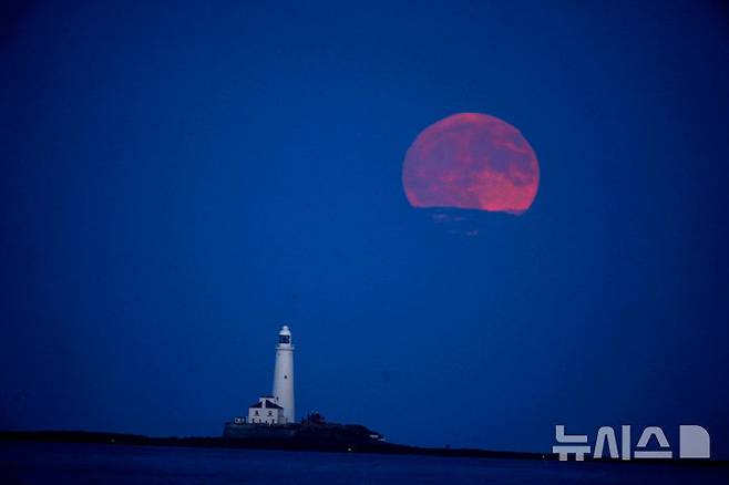 [휘틀리베이=AP/뉴시스] 10일(현지 시간) 영국 휘틀리 베이의 세인트메리스 등대 위로 6월 보름달인 '스트로베리 문'이 떠오르고 있다. 2025.06.11.