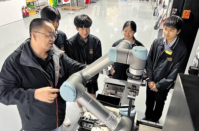 대만 타이중의 공립고등학교인 ‘타이중공고(台中高工)’ 학생들이 기계 앞에서 교사(왼쪽)의 설명을 듣고 있다. 타이중공고는 대만에서 인공지능(AI) 교육을 가장 먼저 도입한 고등학교 중 한곳으로, 졸업생의 85%가 주요 과기대에 진학한다. /이벌찬 특파원