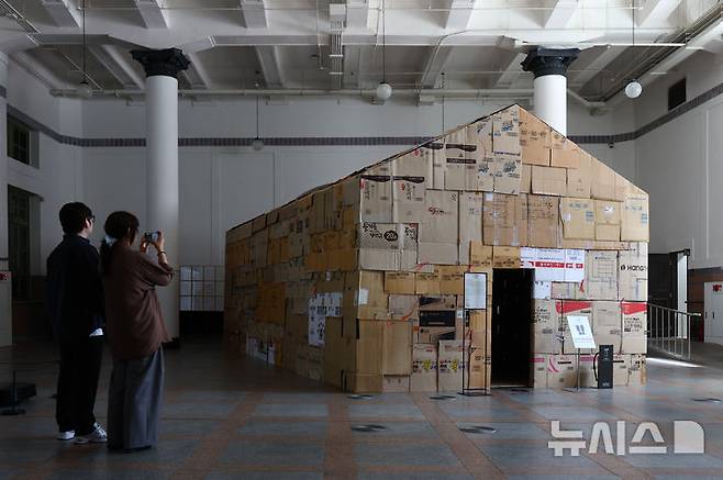 [서울=뉴시스] 황준선 기자 = 12일 서울 용산구 문화역서울 284에서 열린 '우리들의 낙원' 사전 공개 행사에서 관람객들이 이원호 작가의 '부(浮) 부동산' 작품을 관람하고 있다. 오는 13일 개막하는 '우리들의 낙원' 전시는 행복과 이상향을 주제로 하여 과거 사람들이 서울역에서 품어왔던 출발, 설렘, 시대, 위안 등 장소성을 되새기며 행복과 이상향을 탐구하는 여정을 VR, 사진, 설치, 영상 등 50여가지 작품으로 선보인다. 2025.06.12. hwang@newsis.com