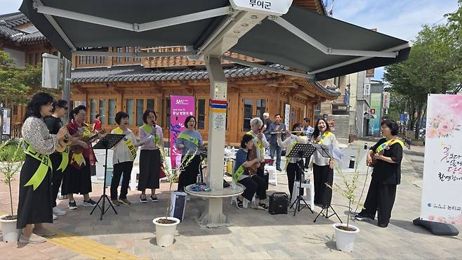 테힐라 사모 합창단 단원들이 12일 충남 부여 백강문화관 앞에서 합창과 연주로 버스킹을 하고 있다.