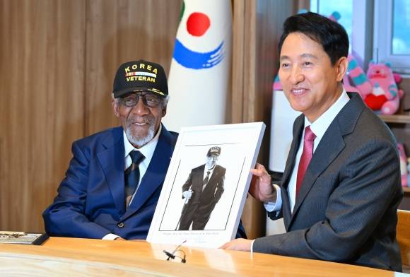 오세훈(오른쪽) 서울시장이 13일 서울 중구 서울시청에서 한국전쟁에 참전했던 미국인 제롬 골더와 ‘프로젝트 솔져’ 작품 사진을 들고 기념 촬영하고 있다.  서울시 제공