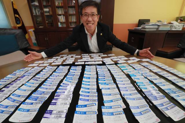 헌혈왕 송태규 시인이 그동안 모은 헌혈증을 보여주며 환하게 웃고 있다. 사진 제공=본인