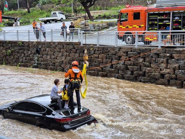 집중호우로 빗길에 미끄러진 승용차가 하천으로 전복돼 고립되었던 모녀가 119구조대에 의해 구조되고 있다. 임경성 기자