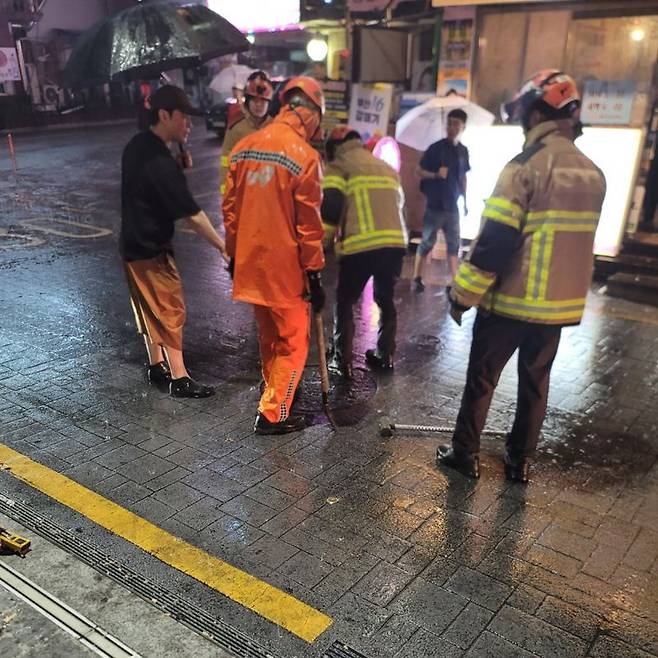 14일 새벽, 부산에 내린 호우로 인해 한 도로의 맨홀뚜껑이 열려 소방 관계자들이 안전조치를 하고 있는 모습. 부산소방재난본부 제공