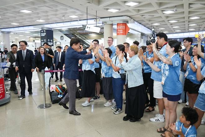출국을 앞둔 입양인들과 오영훈 제주도지사가 제주국제공항에서 따뜻한 하이파이브로 작별 인사를 나누고 있다. (제주관광공사 제공)