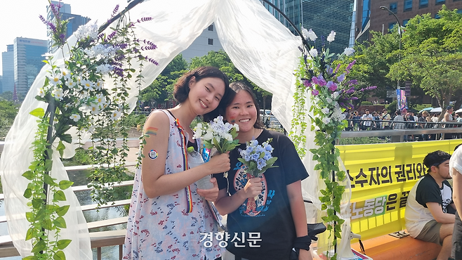 14일 서울 중구 ‘제26회 서울퀴어퍼레이드’ 장소 인근에서 ‘마당극 민중의 부활’이 운영하던 부스에 생활동반자신고서를 낸 김은지씨(29)와 지구(24·활동명)가 기념 사진을 찍고 있다. 강한들 기자