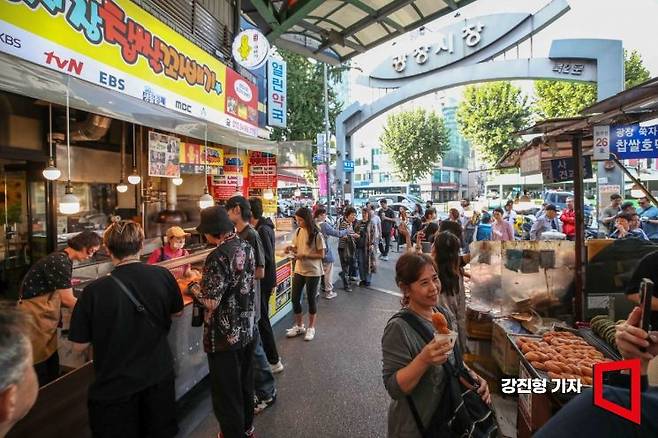 서울 종로구 광장시장에 자리한 유명 꽈배기 상점을 찾은 외국인 관광객들이 꽈배기를 구입하기 위해 줄을 서고 있다.