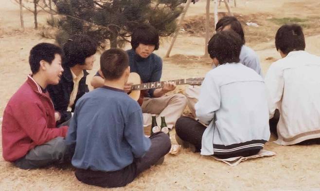 1979년 이재명 대통령(왼쪽 첫째)이 시계 만드는 오리엔트 공장에 다닐 때 남이섬으로 야유회를 가 둥글게 앉아 노래하는 모습. 더불어민주당 제공