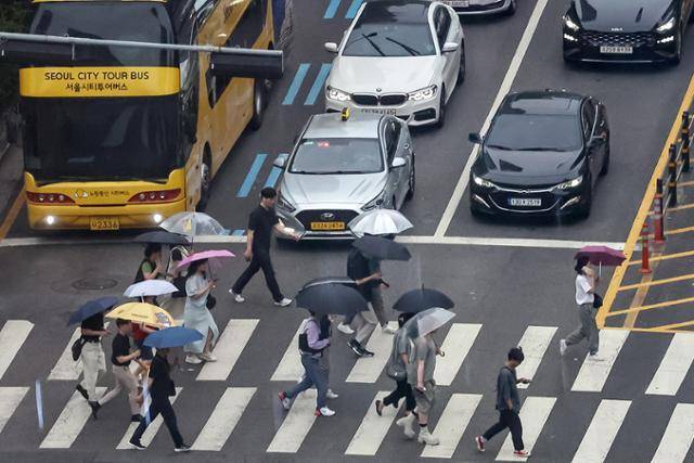 13일 오후 서울 중구 남대문로 일대에서 우산을 쓴 시민들이 횡단보도를 건너고 있다. 뉴스1
