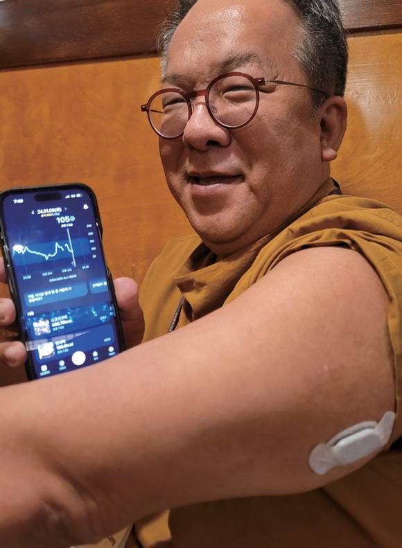 연속혈당측정기를 부착한 팔과 혈당관리 서비스 '파스타' 앱을 보여주고 있는 황희 카카오헬스케어 대표 ⓒ연합뉴스