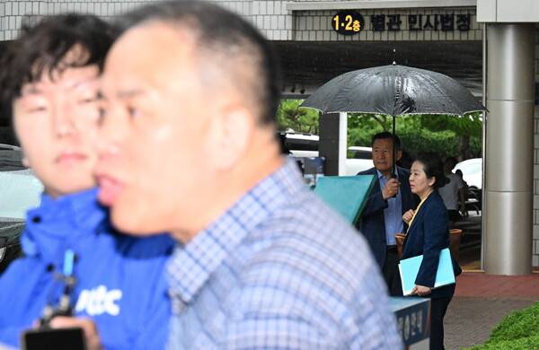 명태균(왼쪽) 씨가 16일 창원지방법원 법정에 들어가기에 앞서 기자들 질문에 답하고 있다. 함께 재판을 받는 김영선 전 국회의원도 기자들 앞에 서고자 멀리서 기다리고 있다. /김구연 기자