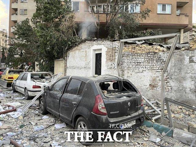 13일(현지시간) 이스라엘의 공습을 받은 이란 테헤란에서 아파트 건물의 잔해가 주차된 차량 위로 떨어져 차량이 파손돼 있다. /뉴시스