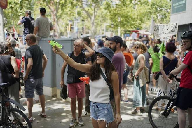 15일(현지시간) 스페인 바르셀로나에서 열린 ‘오버투어리즘’ 반대 시위에서 한 여성이 물총을 들어올리고 있는 모습. AP·연합뉴스