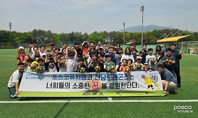 포스코퓨처엠 광양양극소재실 임직원들과 전남드래곤즈 선수들이 지난해 4월 금호동 송죽구장에서 세풍·여천지역 어린이를 위한 축구 클리닉을 실시한 후 참가자 및 가족들과 함께 기념사진을 촬영하고 있다. 포스코퓨처엠 제공
