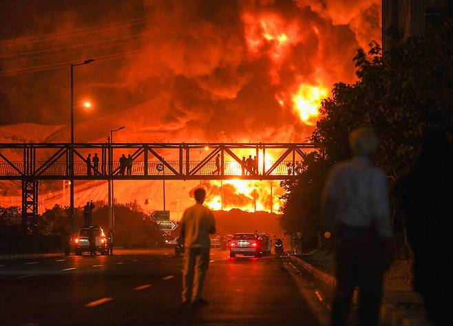 15일 이스라엘군의 공습으로 이란 테헤란의 정유 공장이 화염에 휩싸인 모습을 시민들이 지켜보고 있다. UPI 연합뉴스