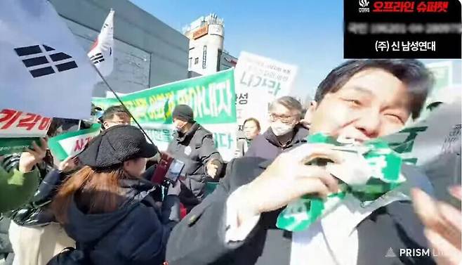 신남성연대 대표 배인규씨가 지난 2월27일 서울시 서대문구 이화여자대학교에서 열린 ‘윤 대통령 탄핵 촉구 시국선언’에서 윤석열 전 대통령 탄핵을 촉구하는 이들이 들고 있던 손팻말을 빼앗아 뜯어 먹고 있다. 신남성연대 유튜브 갈무리