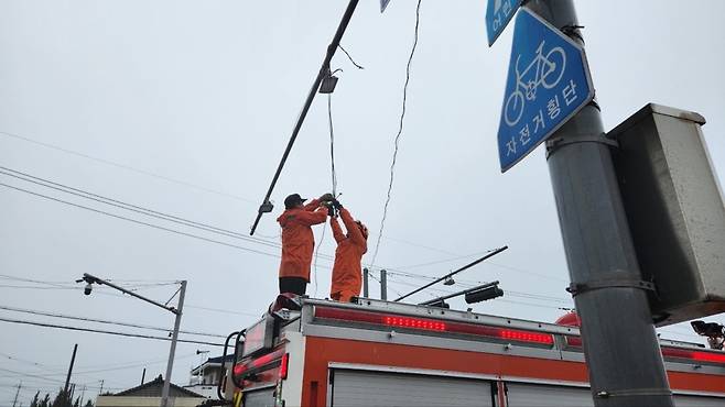 오늘(16일) 오전 제주시 구좌읍 한동리에서 강풍에 신호등 와이어가 늘어져 고정작업이 실시되는 모습
