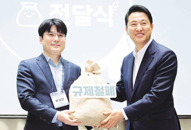 오세훈 서울시장이 지난달 7일 개최된 ‘규제 철폐 100일 성과보고회’에서 시민 제안이 담긴 규제 철폐 모래주머니를 전달받고 있다. 서울시는 오 시장의 전쟁 선포 이후 지금까지 규제 136건을 철폐했다고 밝혔다. 하루 평균 0.8개의 규제가 사라진 것이다. 서울시 제공