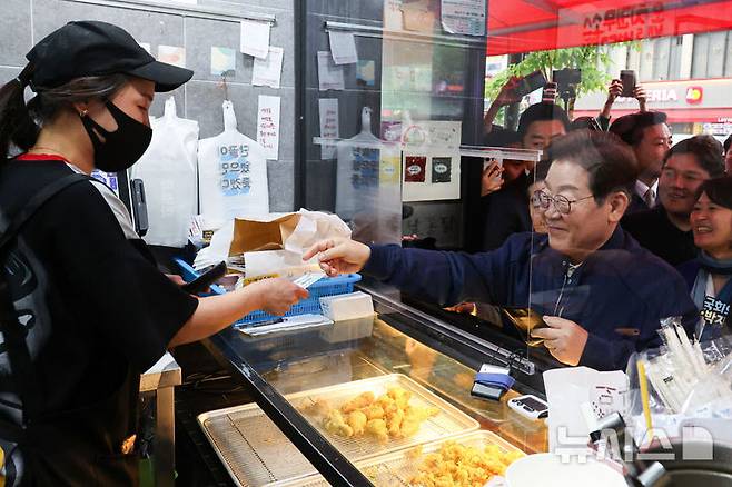 [포천=뉴시스] 조성우 기자 = 이재명 더불어민주당 대선후보가 1일 오후 경기 포천시 신읍사거리 인근에서 골목골목 경청투어를 열고 치킨을 맛본 뒤 지역상품권으로 결제하고 있다. 2025.05.01. xconfind@newsis.com