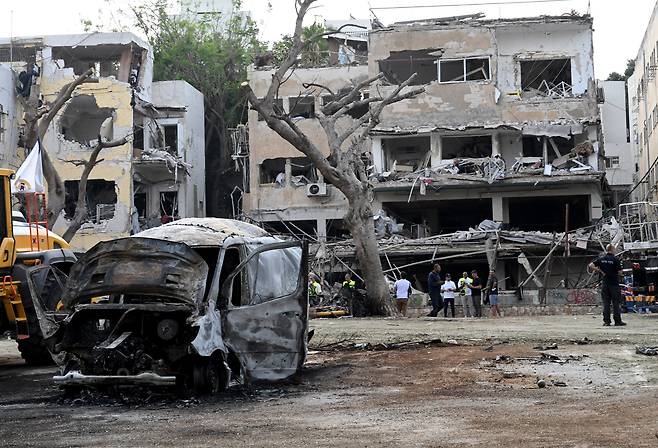 16일 이스라엘의 텔아비브에서 이란의 탄도미사일 공격을 받고 무너진 건물과 부서진 차량 근처에서 경찰 등 당국자들이 피해 상황을 살펴보고 있다./UPI 연합뉴스