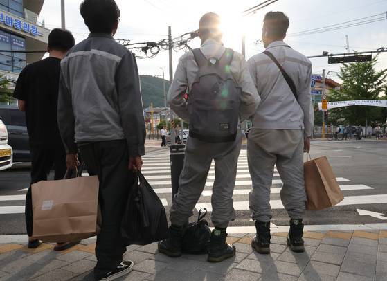 지난 5일 경남 거제시 장평동 삼성중공업에서 퇴근한 외국인 근로자들이 인근 다이소 종이가방을 들고 귀가하고 있다. 송봉근 기자