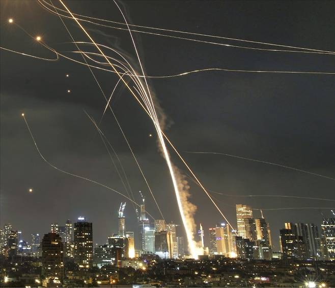 이란이 지난 13일 이스라엘 최대 도시인 텔아비브 등을 향해 미사일 수백 기를 발사했다. 이스라엘의 방공시스템 ‘아이언돔’이 상당수 미사일을 격추했지만 일부 놓친 미사일로 인해 건물이 무너졌다. 이란은 사정거리가 최대 2000㎞인 탄도미사일 ‘하즈 카셈’ 등으로 공격했다. 사진의 굵은 실선은 아이언돔 요격 미사일의 불꽃 궤적.   AP연합뉴스