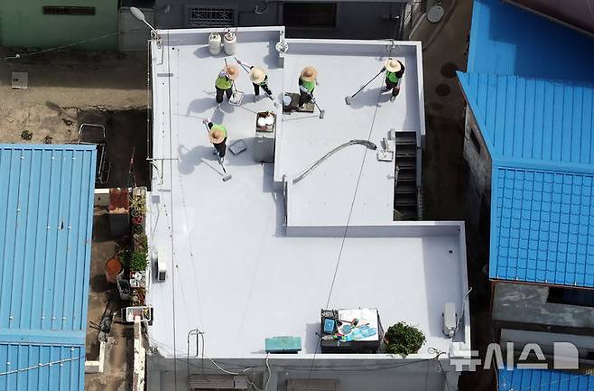 [부산=뉴시스] 하경민 기자 = 부산시자원봉사센터와 7개 기업·기관, 대학생 자원봉사자 등 130여 명이 17일 부산 남구 문현2동 일대 주택 20여 곳의 옥상에서 쿨루프(Cool Roof) 열차단 페인트를 도포하는 봉사활동을 하고 있다.쿨루프는 태양열 반사 및 열 차단 효과가 있는 친환경 도료를 주택 지붕 및 옥상에 도포해 실내온도를 효과적으로 낮추는 기술이다. 2025.06.17. yulnetphoto@newsis.com