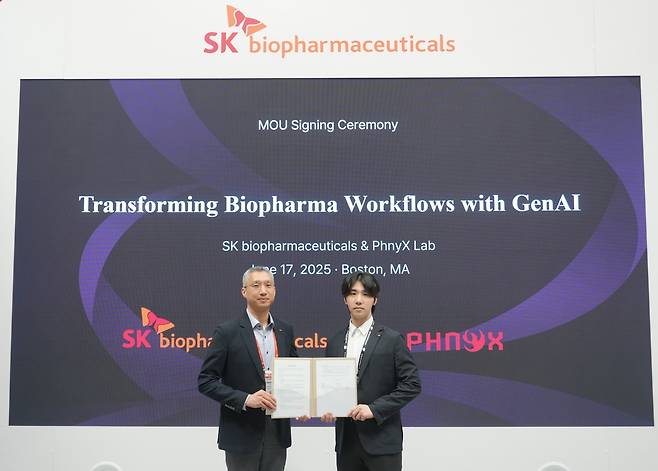 SK Biopharmaceuticals Head of Strategy Yoo Chang-ho (left) and PhnyX Lab CEO Bae Min-seok pose for a photo after signing a business agreement for collaboration on AI-driven drug development at the SK Biopharmaceuticals booth during Bio USA 2025 in Boston, Tuesday. (SK Biopharmaceuticals)
