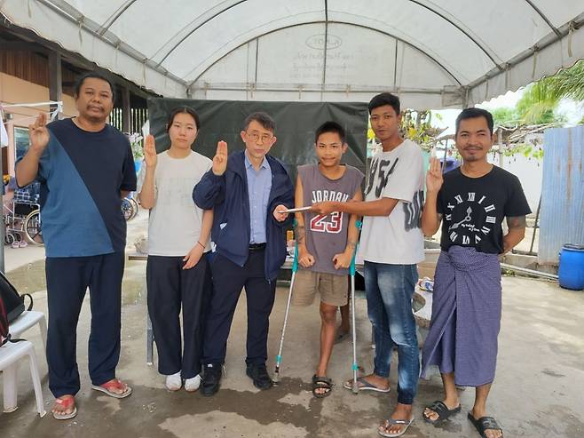 Park Eun-hong (third from left), professor and director of the Resource Center for Asian NGOs at Sungkonghoe University, and Jeon Ye-rin (second from left), deputy head of the Democracy School Without Borders, deliver aid funds to injured civilians during a visit to the Sunshine Care Center, a rehabilitation camp, on June 14. (The Resource Center for Asian NGOs)