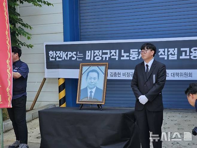 [태안=뉴시스] 김덕진 기자=김영훈 태안화력 한전KPS비정규직지회장이 18일 오전 고 김충현씨 사망사고가 일어난 발전소 내 한전KPS 태안사무처 건물 입구에 영정 사진을 안치하고 추모 준비를 하고 있다. 2025.06.18. spark@newsis.com