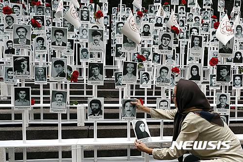 【뉴욕=AP/뉴시스】미국 뉴욕 유엔본부 앞에서 2016년 9월 20일 한 여성이 이란에서 처형된 약 3만명의 사진을 일일이 붙이는 시위에 참가하고 있다. 이 시위를 조직한 이란미국커뮤니티기구는 이란 정부의 인권 탄압을 비판하고 민주적 변화를 촉구했다. 2025.06.19.