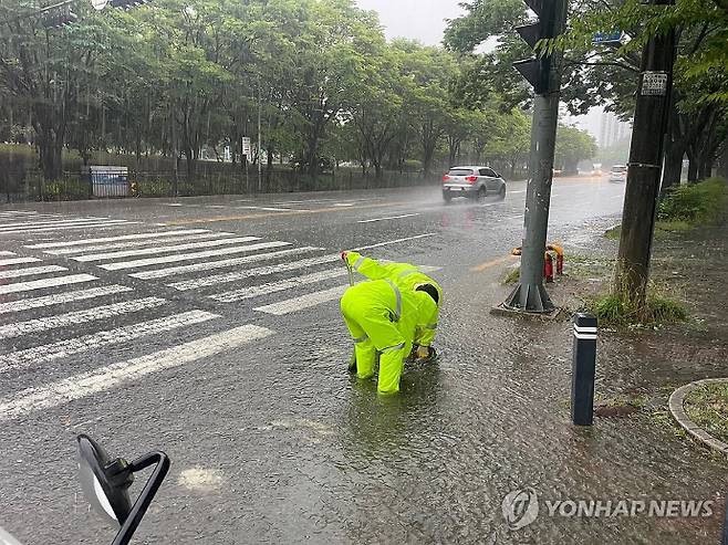 21일 광주 광산구 첨단2동에서 광산구 관계자들이 폭우로 이탈한 맨홀 뚜껑을 정비하고 있다. 연합뉴스