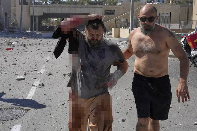 20일(현지 시간) 이스라엘 하이파에서 이란의 미사일 공격으로 부상한 남성이 부축을 받으며 대피하고 있다. (사진=뉴시스)