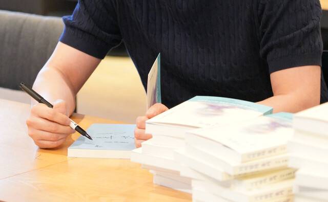 ‘기억함의 용기’ 출간에 참여한 청년이 북토크를 찾은 독자에게 사인을 해주고 있다. ⓒ이요셉 작가